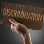 cardboard sign that says discrimination