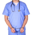 Doctor with stethoscope in handcuffs isolated on white