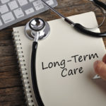 Women Hand Write "LONG-TERM CARE" On Note Book