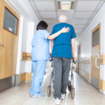Asian nurse helping elder man walking in rehab facility