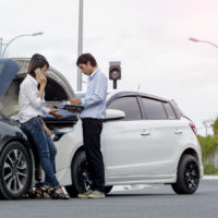 Woman driver calls for instruction during insurance agent review the dammage of the car after accident