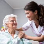 Smiling nurse and old woman patient at wheelchair