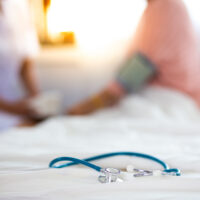 Closeup of stethoscope on blur photo of Nurse measuring blood pressure of senior woman background