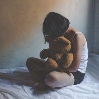 concept photo of Sexual assault, young girl sit on a bed in a bedroom.