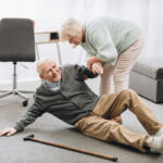 old woman helping to stand up husband who falled down on floor