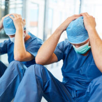 Two exhausted surgeons with hands on their heads