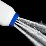 Talcum powder pouring from bottle on black background