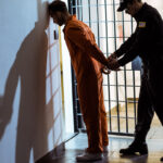 side view of prison officer wearing handcuffs on prisoner