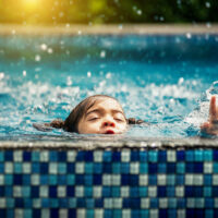 Baby girl drowning in pool. Danger and children Concept. Pools and swimming lessons.